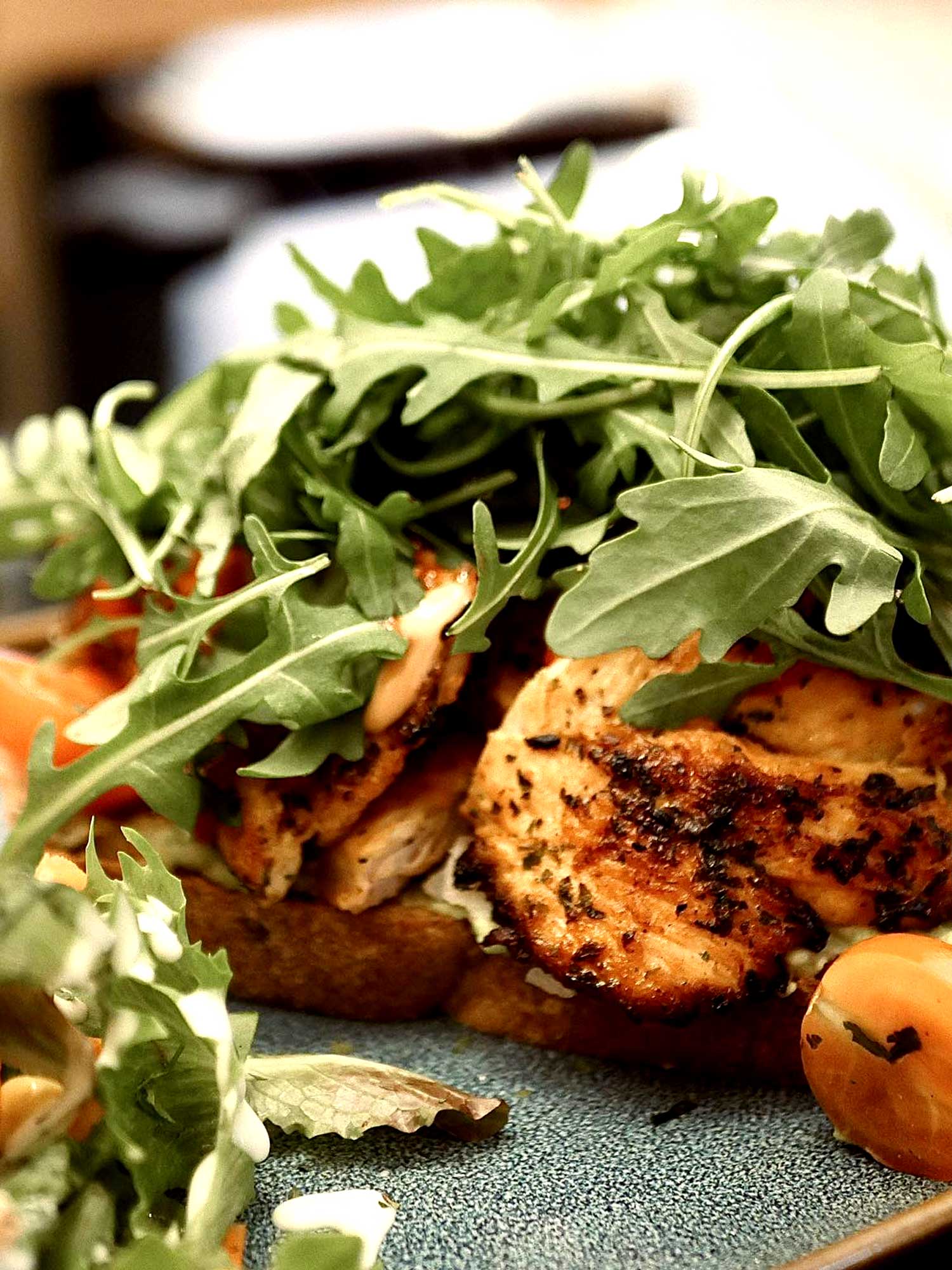 Sweety chicken - Pain au levain, poulet mariné doux, poivrons, oignons, gratiné à l'Emmental, Roquette servis de salade